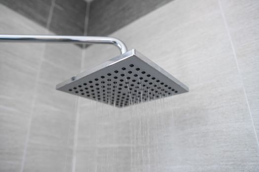 Water flowing from the square shower head in a modern bathroom. Shower in the bathroom with water spray or water. A stream of fresh water from the shower head to clean the dirty body