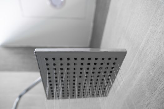 Water flowing from the square shower head in a modern bathroom. Shower in the bathroom with water spray or water. A stream of fresh water from the shower head to clean the dirty body