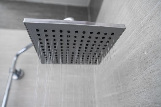 Water flowing from the square shower head in a modern bathroom. Shower in the bathroom with water spray or water. A stream of fresh water from the shower head to clean the dirty body