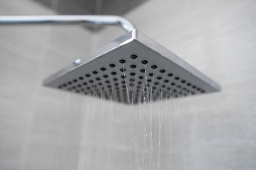 Water flowing from the square shower head in a modern bathroom. Shower in the bathroom with water spray or water. A stream of fresh water from the shower head to clean the dirty body