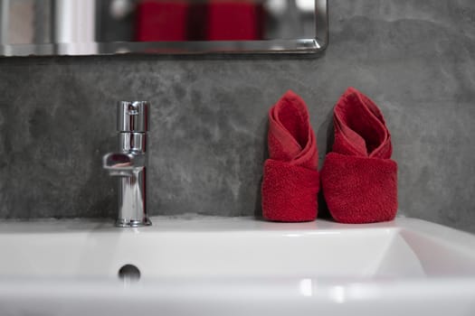 Modern stainless steel faucet with wash basin sink with a two red towels on it . Counter bathroom interior contemporary. Luxury and stylish design bathroom with a concrete style walls