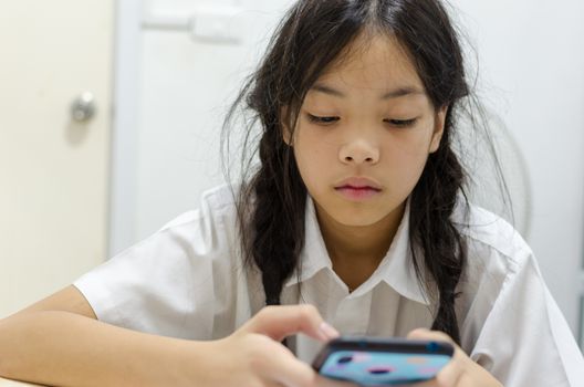 Young schoolgirl addicted to mobile phone games. Makes him not interested in doing homework.