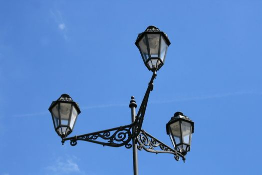 Street light with three lamps, blue sky in the background 