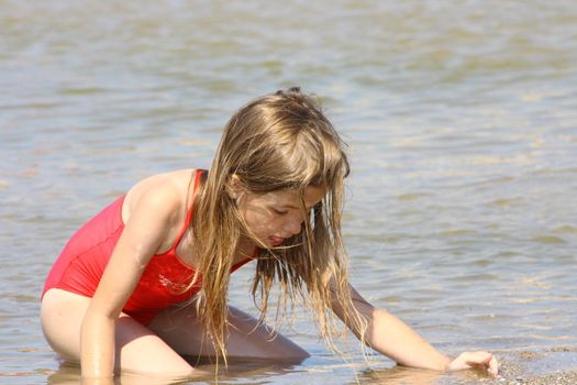 Blonde girl looking for a treasure on the beach