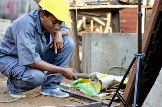 Young woman soldering to make an iron door.