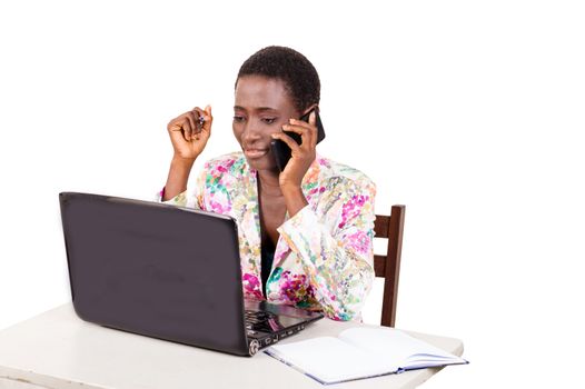 Young happy business woman working on a laptop by calling on mobile phone
