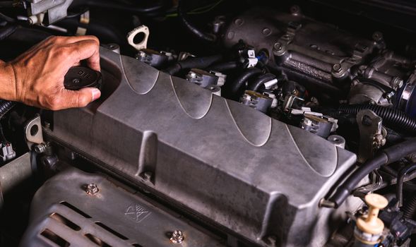 Hand of auto mechanic technician service engine and open the engine oil lid on car in garage