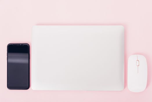 Top view of modern technology smart phone mobile and computer laptop close cover on pink background with copy space