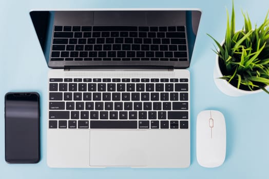 Top view of modern technology smart phone mobile and computer laptop on blue background with copy space