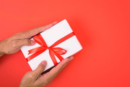 Valentine's Day Concept, Top view Flat lay, Hand holding gift box on red background with copy space for your text