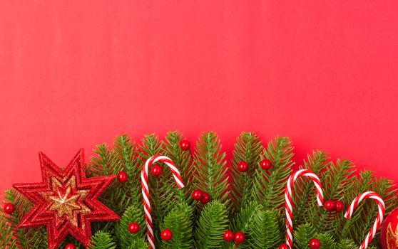 Happy new year or christmas day top view flat lay fir tree branches and ornaments decoration on red background with copy space for your text