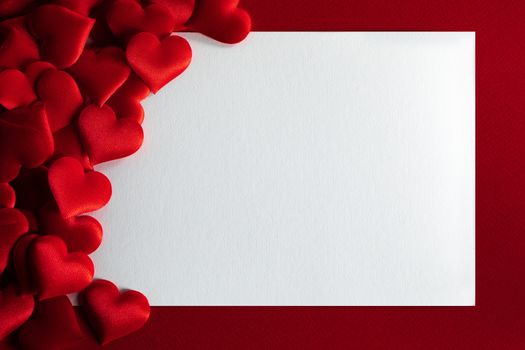 Valentine's day many red silk hearts background , border frame with white card with copy space, love concept