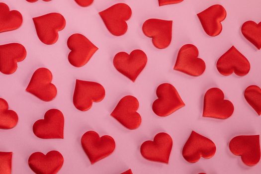 Valentine's day many red silk hearts on pink paper background, love concept