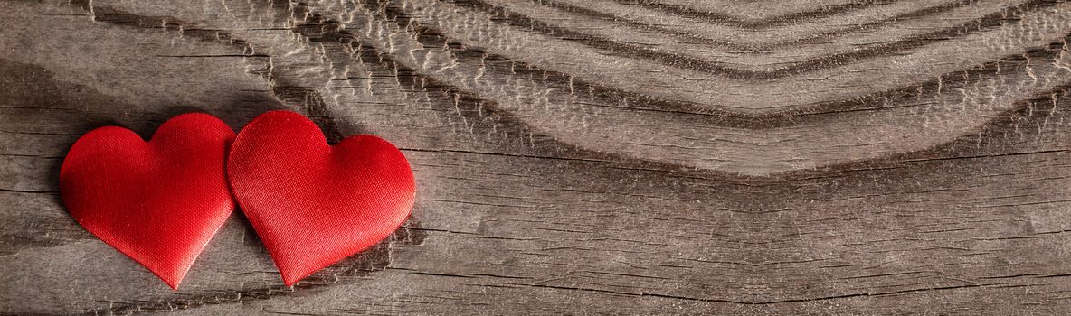 Valentine's day two red silk hearts on wooden background, love concept