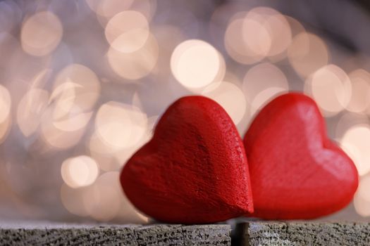 Two red wooden hearts symbol of love on background with beautiful bokeh party lights, Saint Valentine Day celebration