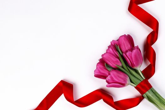 Valentines day pink tulip flowers and red ribbon isolated on white background