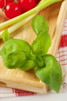 Fresh basil and vegetables on wooden serving tray