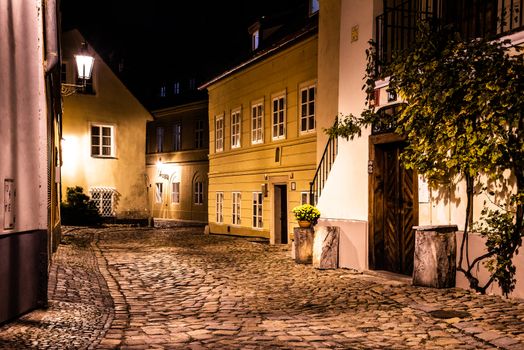 Narrow cobbled street in old medieval town with illuminated houses by vintage street lamps, Novy svet, Prague, Czech Republic. Night shot.