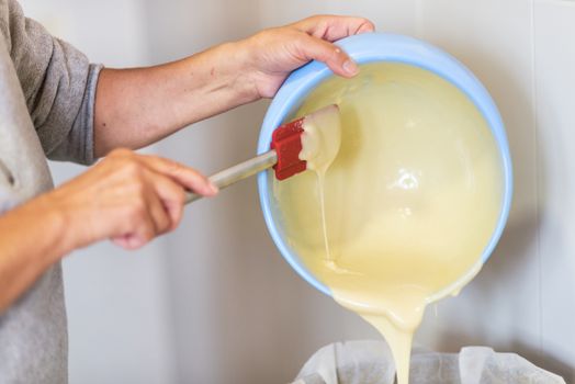 Senior woman hands pouring dough into a baking tray. Shallow deep of field.