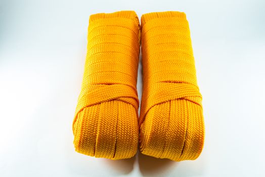 Orange rope rolls flat on white background.