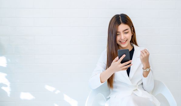 Business women wear white clothes glad to play mobile phone in a white background