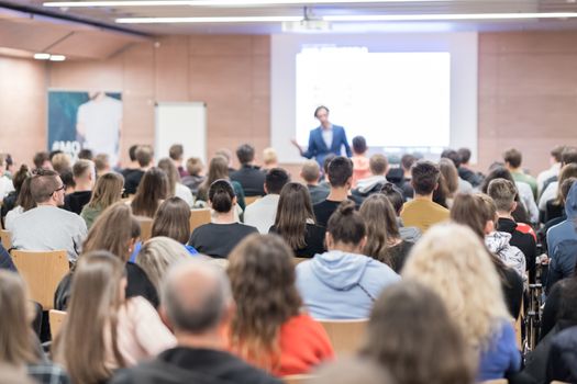 Speaker giving a talk in conference hall at business event. Audience at the conference hall. Business and Entrepreneurship concept. Focus on unrecognizable people in audience.