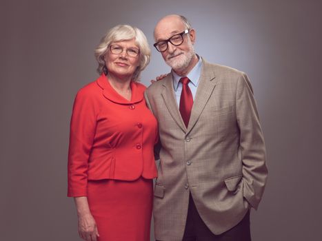 Happy elderly seniors couple studio portrait on gray background