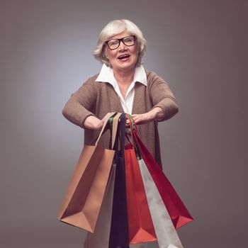 Shopper senior woman holding shopping bags possing happy smiling and excited