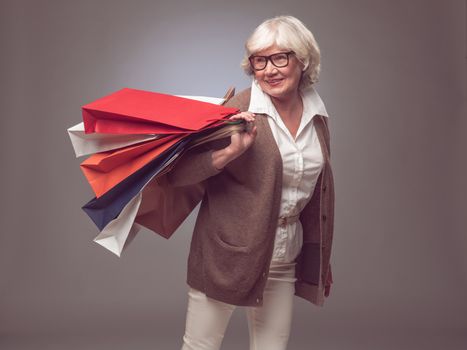 Shopper senior woman holding shopping bags possing happy smiling and excited