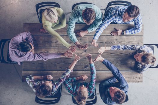 Business people team giving high five gesture and sitting at table in office top view