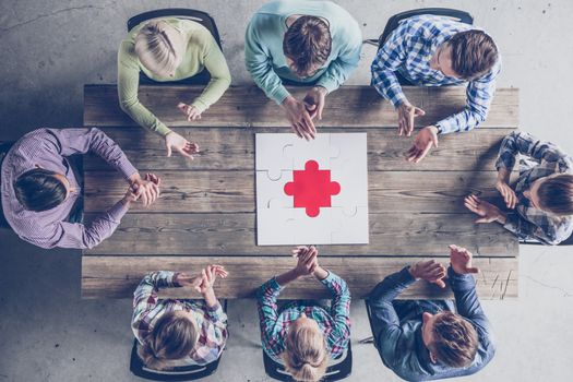 Business team with solved puzzle on wooden table, teamwork success concept