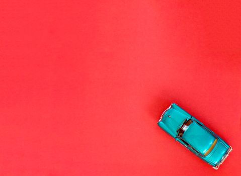 Toy car on a red background with copying space. The car model is made of blue metal.