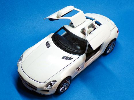 Car sports car in the Studio. Children's toy. Car with folding doors on a blue background. Expensive coupe in a car dealership.