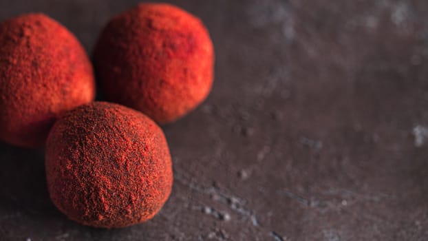 Red homemade truffle coated dry beet powder on dark background. Copy space right for text or design, banner.