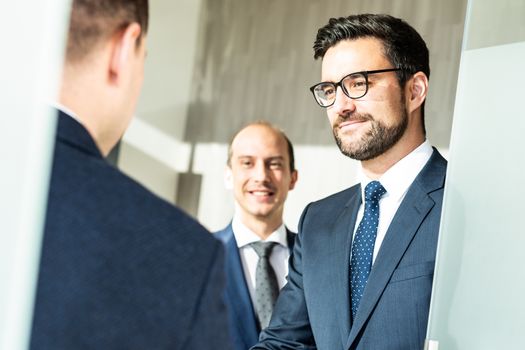 Group of confident business people greeting with a handshake at business meeting in modern office. Closing the deal agreement by shaking hands. Business and entrepreneurship success concept.