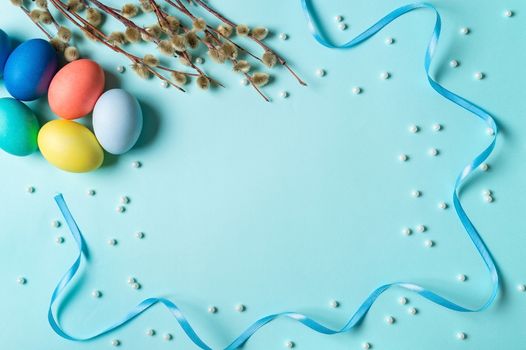 Orthodox Easter concept. Colorful eggs and pussy willow branches on blue background with empty chalkboard. Copy space for greetings, text or design. Top down view or flat lay