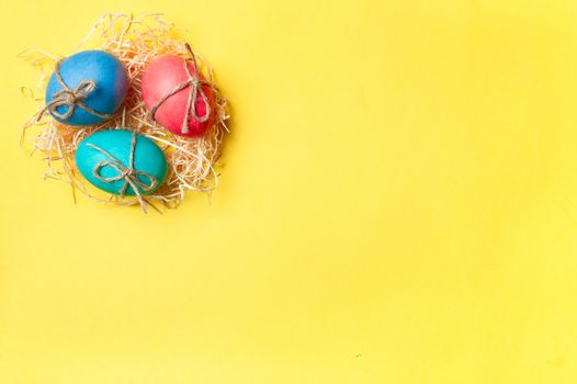 Easter concept. Colorful eggs on bright yellow background with copy space for text. Top down view or flat lay