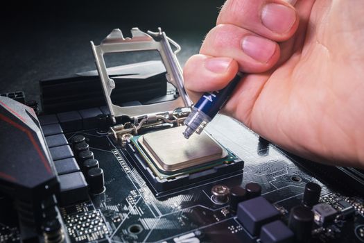 Close up to technician squeezing or application the thermal paste compound on the top of main cpu in the socket.