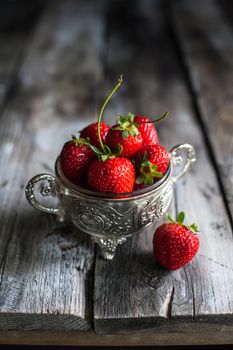 Strawberries in a cup on a wooden background