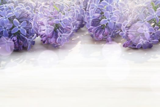 Beautiful floral blank for design - a border of lilac flowers on a wooden table with copy space for text.