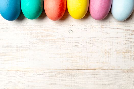 Easter concept. Colorful eggs on white wooden background with copy space for text. Top down view or flat lay