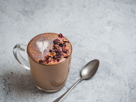 Trendy Coffee with edible glitter and dried rose petals. Cup of sparkly coffee or diamond cappuccino on gray table. Copy space for text