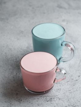 Trendy drink: Blue and pink latte. Top view of hot butterfly pea latte or blue spirulina latte and pink beetroot latte on gray cement textured background. Copy space for text.