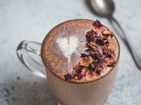 Trendy Coffee with edible glitter and dried rose petals. Cup of sparkly coffee or diamond cappuccino on gray table. Copy space for text