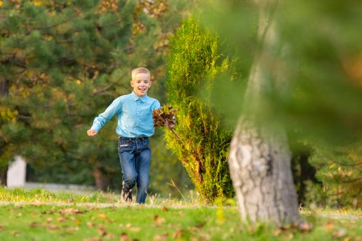 The boy happily runs through the park on the green grass