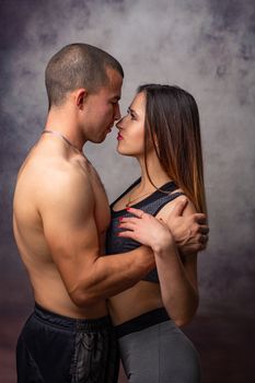 Girl and guy of athletic physique in sports clothes hug each other