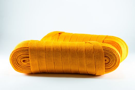 Orange rope rolls flat on white background.