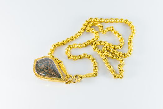 Gold necklaces and amulets on white background.