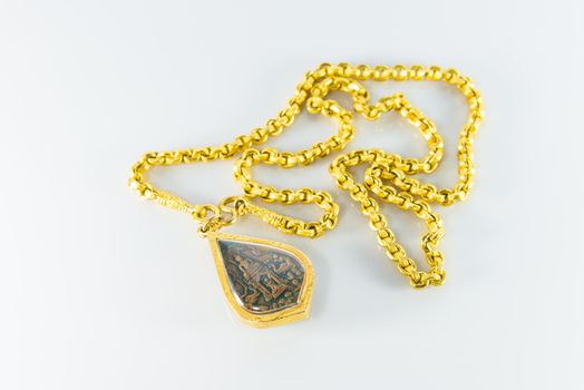 Gold necklaces and amulets on white background.