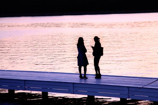 Two girls are late in the evening on the quay of the Moscow canal. Moscow. 12.09.2014